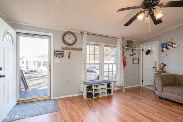 foyer entrance with ceiling fan, hardwood / wood-style floors, lofted ceiling, a textured ceiling, and ornamental molding