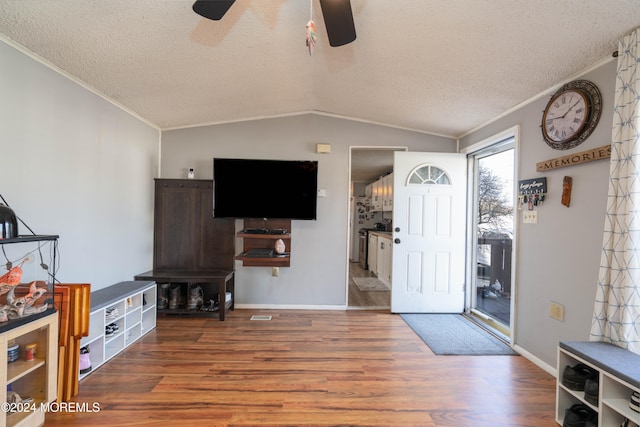 foyer entrance featuring a textured ceiling, crown molding, hardwood / wood-style floors, and lofted ceiling