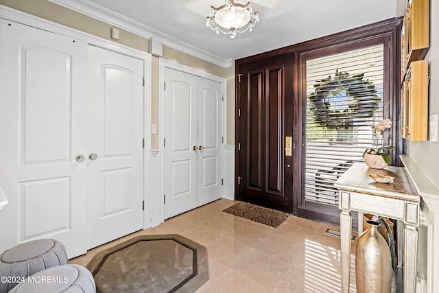 tiled entrance foyer featuring a chandelier and ornamental molding