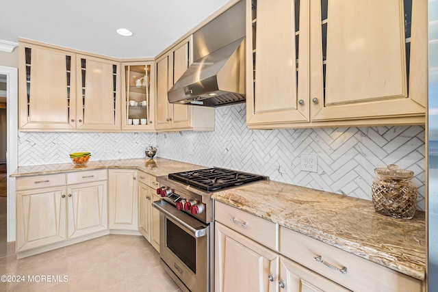 kitchen with tasteful backsplash, light brown cabinets, wall chimney exhaust hood, and luxury stove