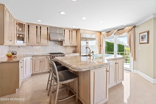 kitchen with a kitchen island with sink, sink, decorative backsplash, premium appliances, and extractor fan