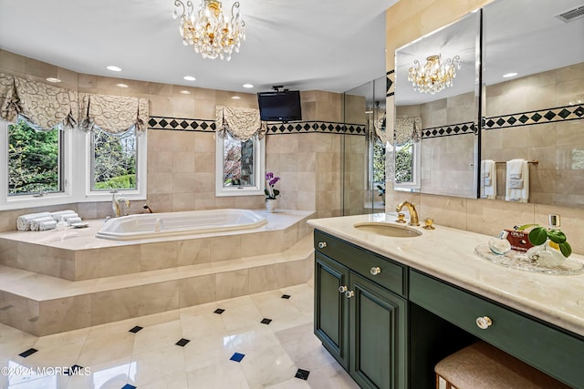 bathroom featuring an inviting chandelier, tile patterned flooring, a relaxing tiled tub, vanity, and tile walls