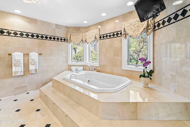 bathroom with a relaxing tiled tub, tile walls, and a wealth of natural light