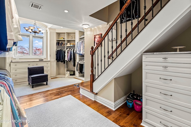 stairs with hardwood / wood-style floors and an inviting chandelier