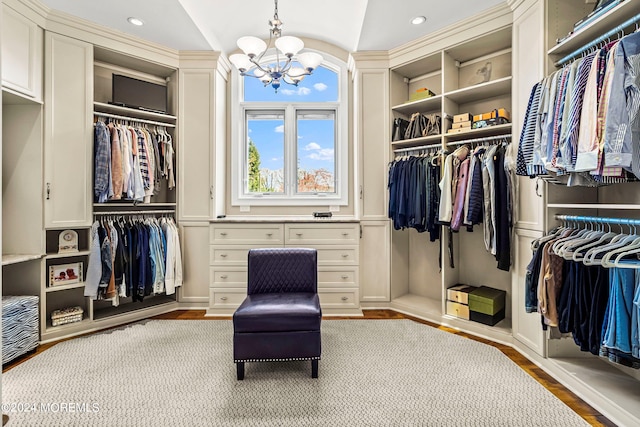 walk in closet featuring an inviting chandelier, vaulted ceiling, and light hardwood / wood-style floors