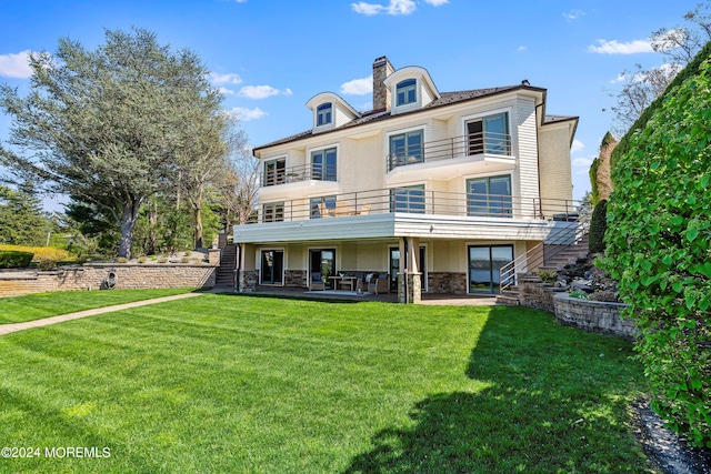 rear view of house with a balcony, a yard, and a patio