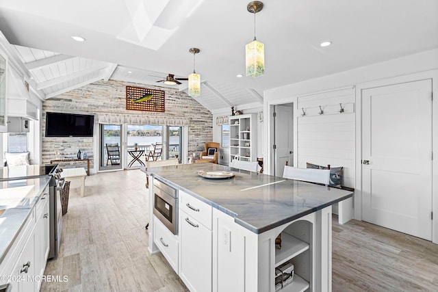 kitchen featuring white cabinetry, stainless steel microwave, vaulted ceiling with beams, pendant lighting, and a kitchen island