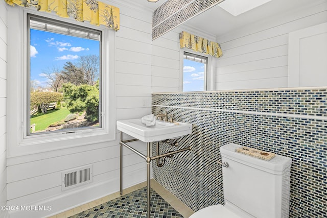 bathroom featuring toilet, tile walls, and wooden walls