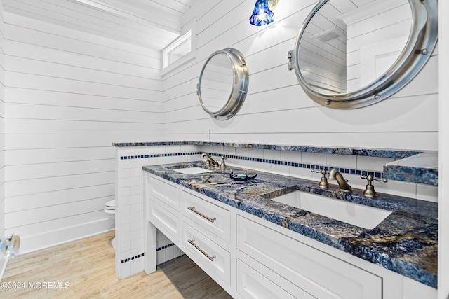 bathroom with wood walls, hardwood / wood-style floors, vanity, and toilet