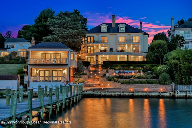 back house at dusk with a balcony and a water view