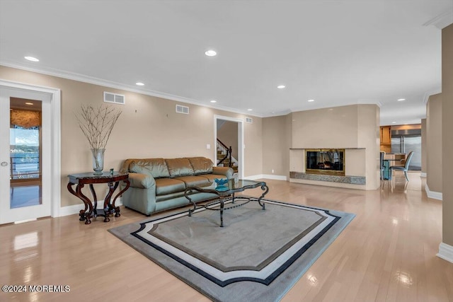 living room featuring light hardwood / wood-style floors, ornamental molding, and a premium fireplace