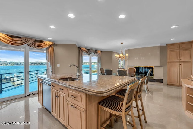 kitchen with light stone countertops, stainless steel dishwasher, sink, a water view, and a center island with sink