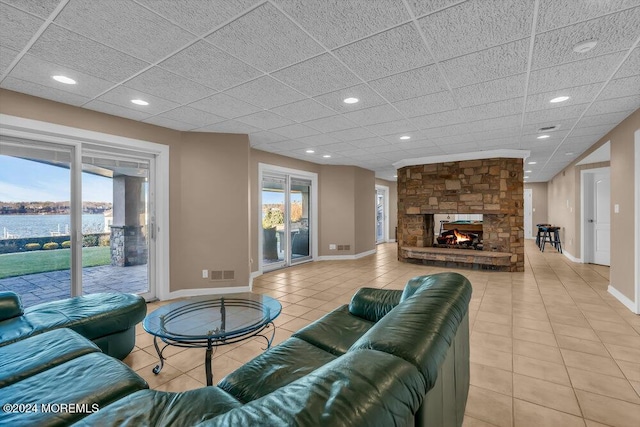 living room featuring plenty of natural light, a water view, light tile patterned floors, and a fireplace