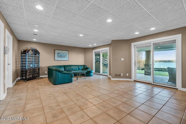 unfurnished living room featuring light tile patterned flooring and a water view