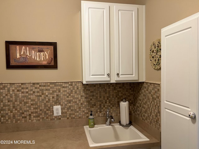 kitchen featuring decorative backsplash, white cabinetry, and sink