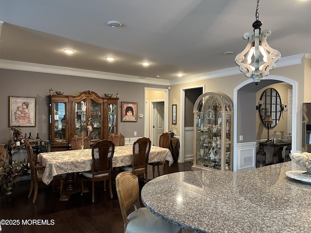 dining space with dark wood-type flooring, ornamental molding, and a notable chandelier