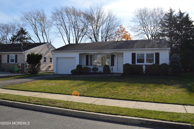 ranch-style house with a garage, covered porch, and a front lawn