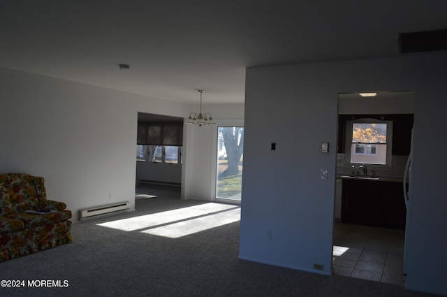 unfurnished living room with a baseboard radiator, a wealth of natural light, and a notable chandelier