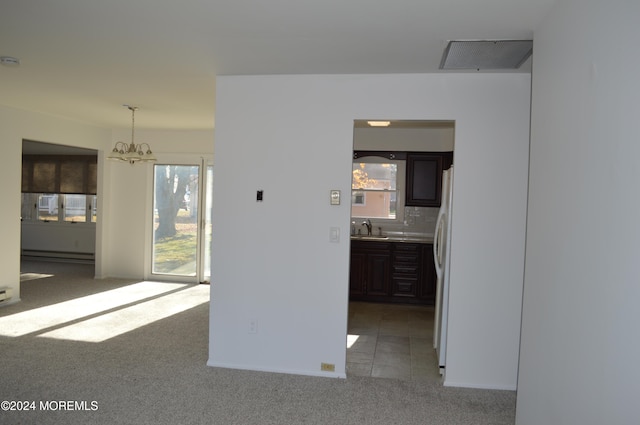 carpeted spare room with baseboard heating, a notable chandelier, and sink