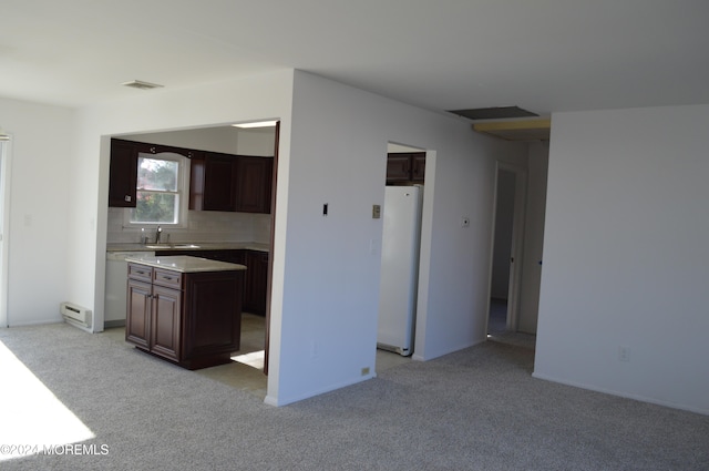 kitchen with dark brown cabinetry, a center island, light carpet, white fridge, and decorative backsplash