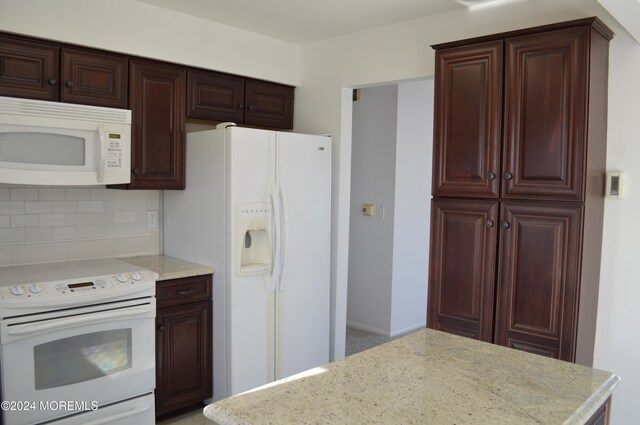 kitchen featuring decorative backsplash, white appliances, and light stone counters