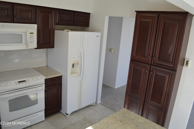 kitchen featuring backsplash, light stone counters, light tile patterned floors, and white appliances