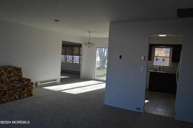 unfurnished living room featuring an inviting chandelier, light colored carpet, sink, and a baseboard heating unit