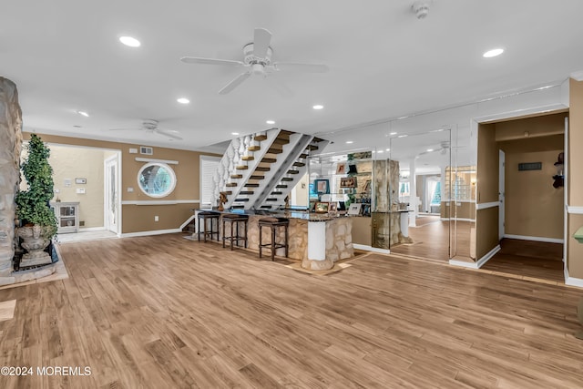 bar with hanging light fixtures, light hardwood / wood-style flooring, and ceiling fan