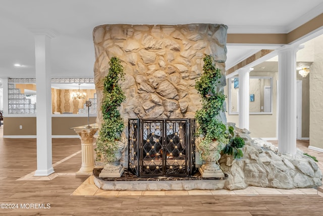 details with hardwood / wood-style flooring, a stone fireplace, ornate columns, and crown molding