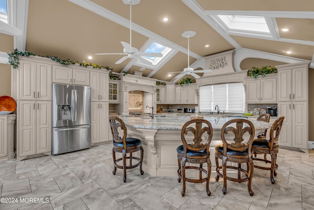 kitchen featuring a skylight, high vaulted ceiling, stainless steel refrigerator with ice dispenser, a breakfast bar area, and decorative backsplash