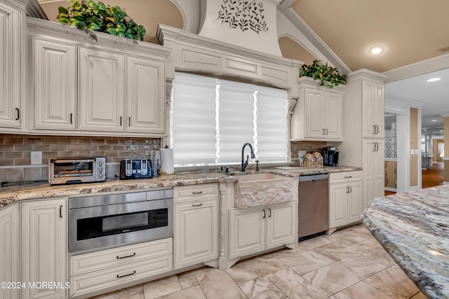 kitchen with backsplash, ornamental molding, vaulted ceiling, and appliances with stainless steel finishes