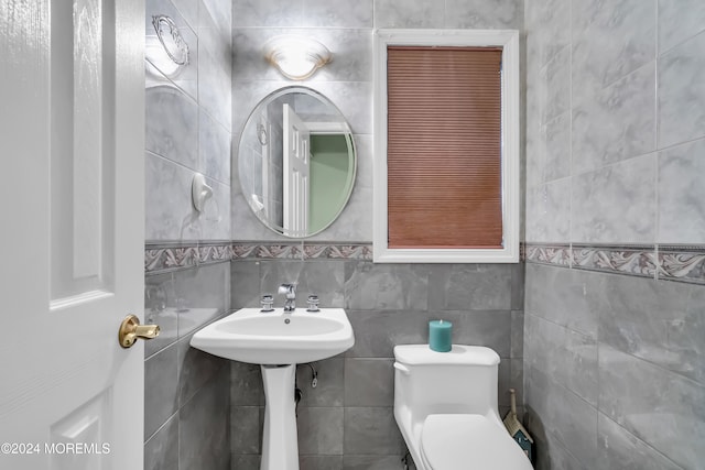 bathroom featuring toilet and tile walls