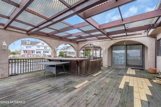 wooden deck featuring a pergola, a grill, a water view, and exterior bar