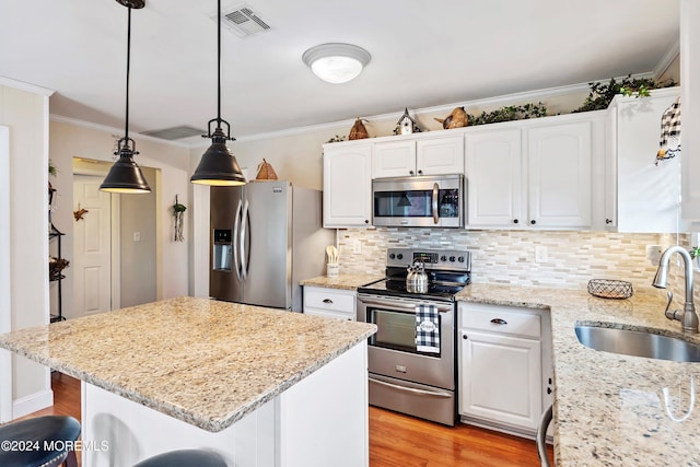 kitchen featuring light stone countertops, stainless steel appliances, sink, decorative light fixtures, and white cabinets