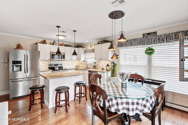 dining space featuring light wood-type flooring, a baseboard radiator, ornamental molding, and sink