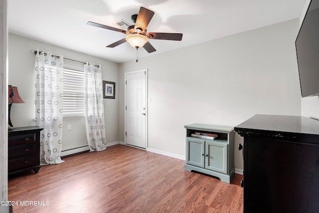 interior space with hardwood / wood-style flooring, ceiling fan, and a baseboard heating unit