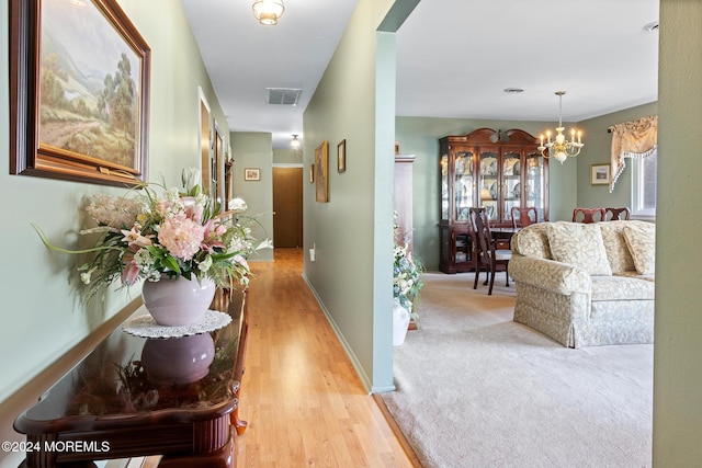 corridor featuring light hardwood / wood-style floors and an inviting chandelier