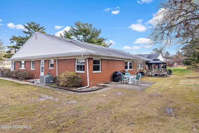 rear view of property featuring a gazebo, central AC unit, a patio, and a lawn