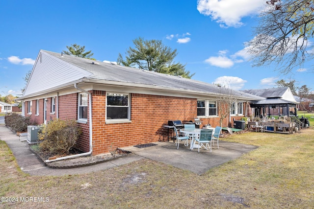 rear view of property featuring a gazebo, a patio area, and a lawn