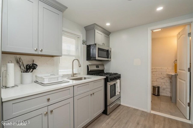 kitchen featuring appliances with stainless steel finishes, light hardwood / wood-style flooring, gray cabinetry, and sink