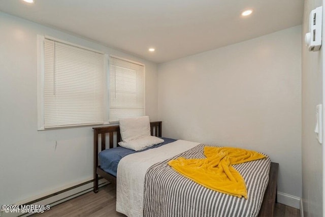 bedroom with baseboard heating and dark wood-type flooring