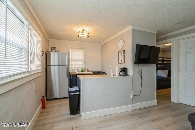 kitchen featuring stainless steel refrigerator, kitchen peninsula, light hardwood / wood-style floors, a textured ceiling, and ornamental molding