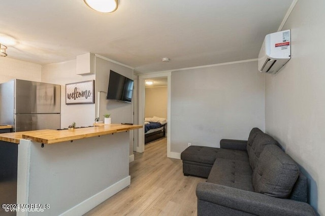 kitchen with a breakfast bar, wooden counters, light hardwood / wood-style flooring, stainless steel refrigerator, and a wall unit AC