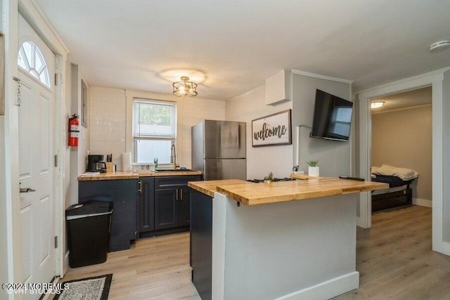 kitchen with wood counters, a kitchen breakfast bar, light hardwood / wood-style floors, and stainless steel refrigerator