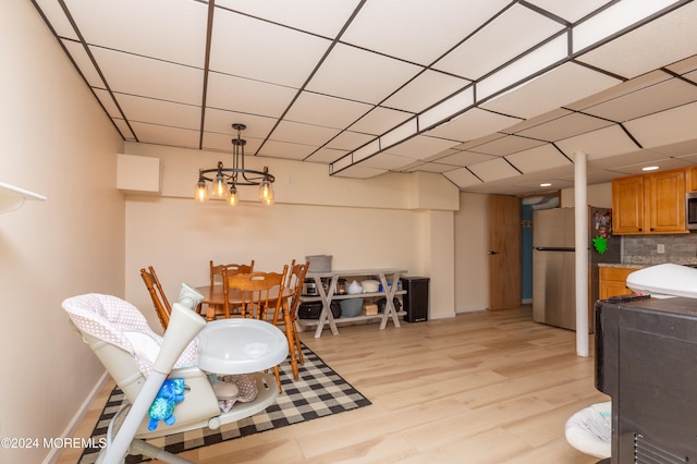 dining space with a drop ceiling and light wood-type flooring