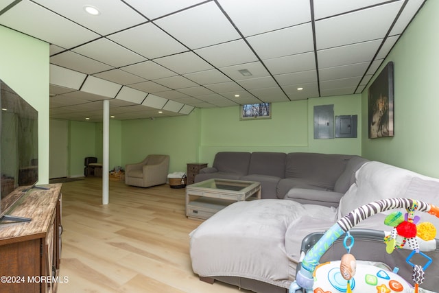 living room featuring a paneled ceiling, electric panel, and light wood-type flooring