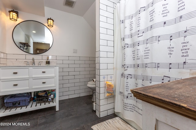 bathroom featuring tile patterned floors, vanity, toilet, and tile walls