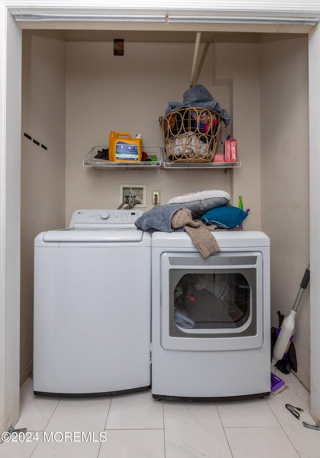 clothes washing area with light tile patterned flooring and independent washer and dryer