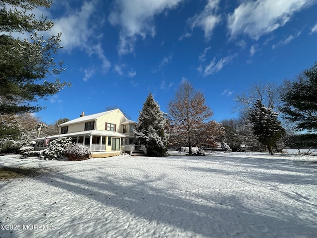 view of snowy exterior with a sunroom