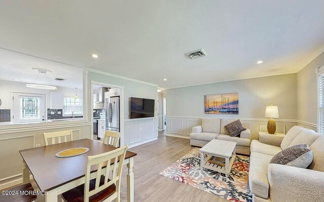 living room featuring crown molding, sink, and light hardwood / wood-style floors